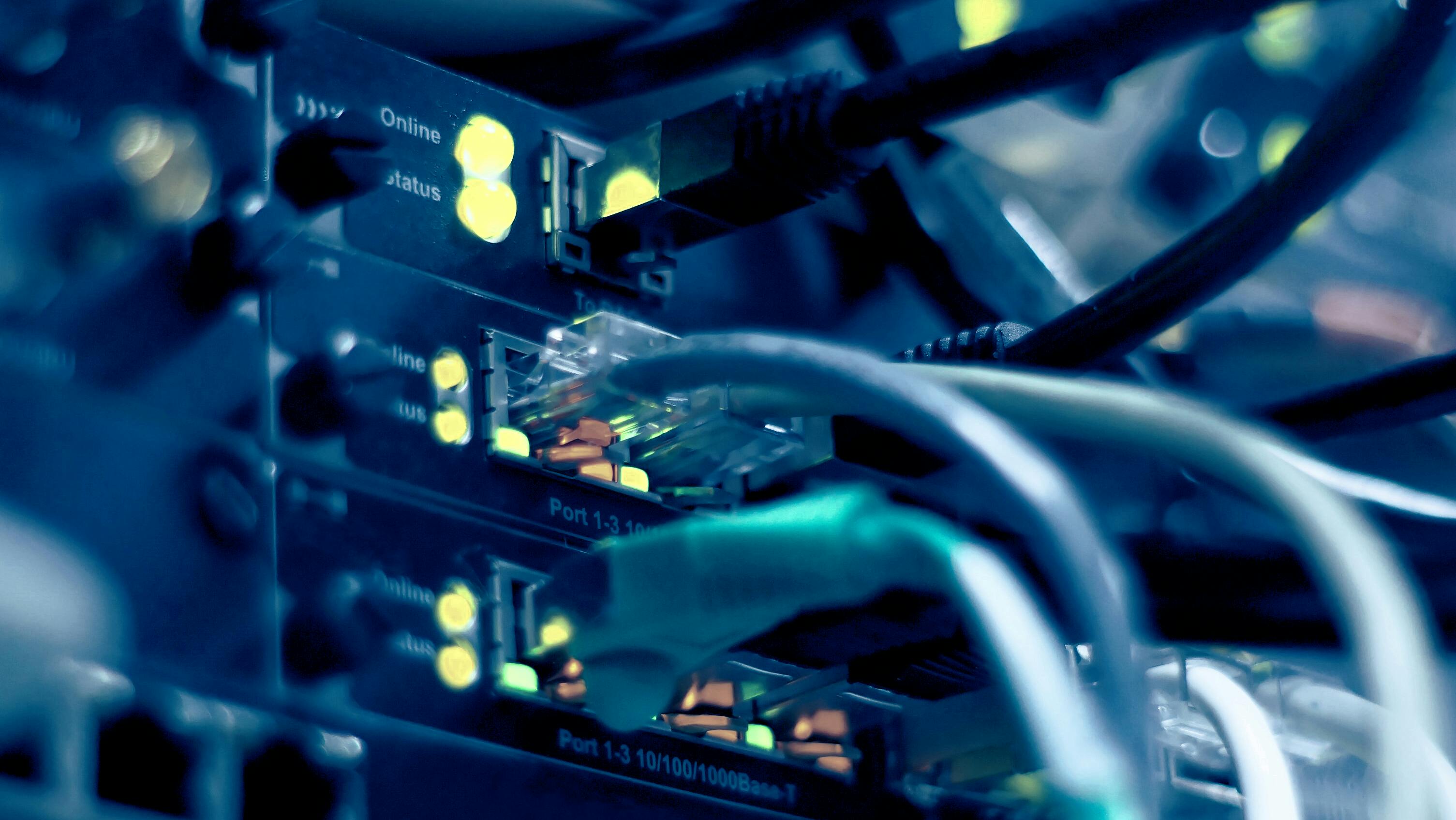 Close-up of network switch ports with ethernet cables and glowing yellow status indicator lights.