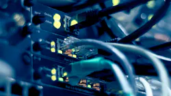 Close-up of network switch ports with ethernet cables and glowing yellow status indicator lights.