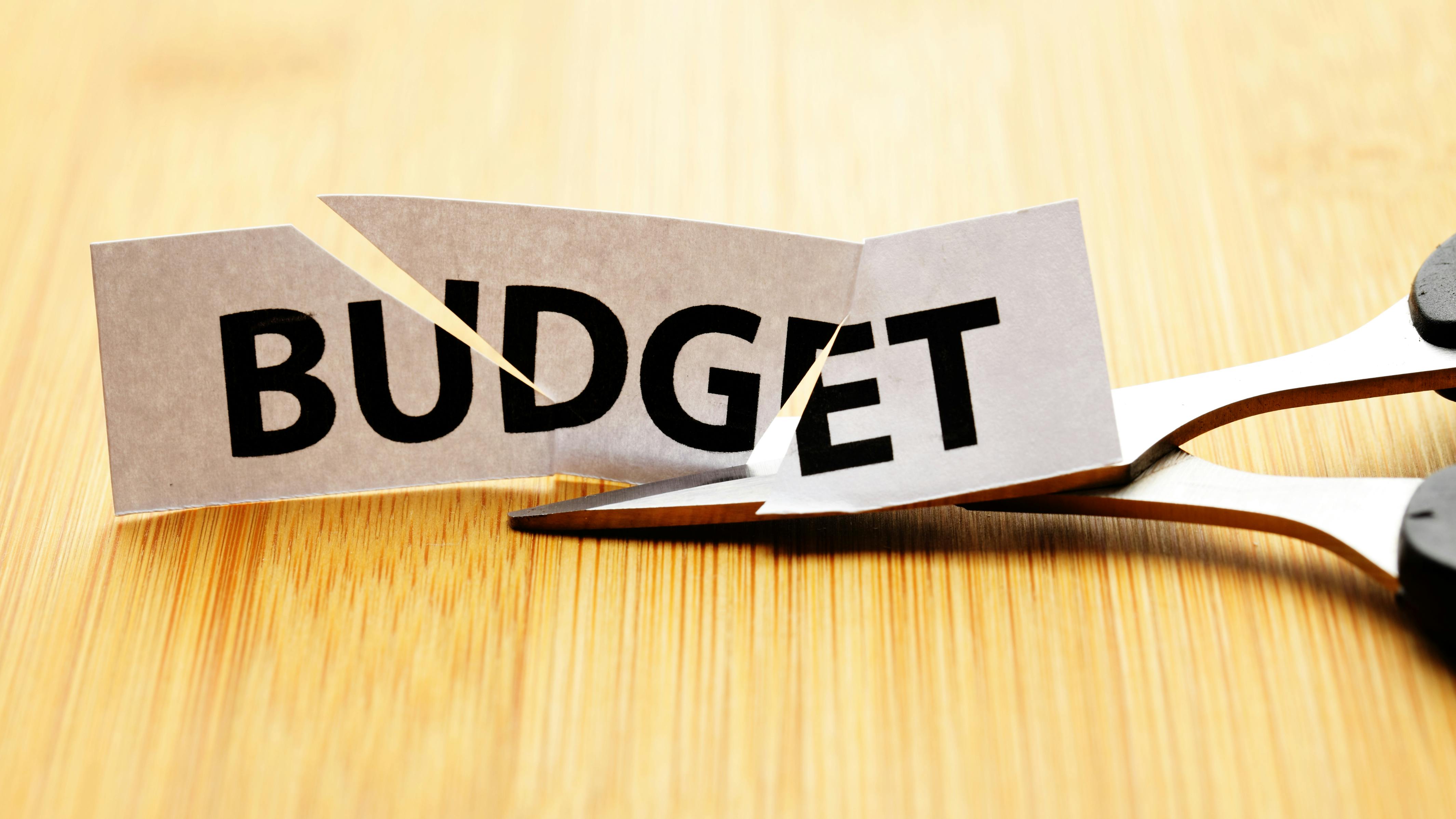 Paper with 'Budget' cut through it next to pair of scissors