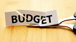 Paper with 'Budget' cut through it next to pair of scissors Paper with 'Budget' cut through it next to pair of scissors
