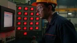 A factory worker in a hard hat and safety glasses monitors a control panel with red LED displays. A factory worker in a hard hat and safety glasses monitors a control panel with red LED displays.