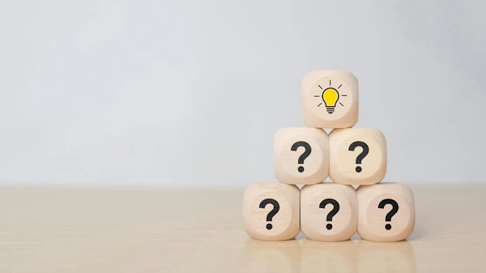 Wooden blocks stacked in a pyramid with question marks, topped by a block with a lightbulb icon