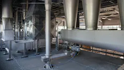The interior of a modern factory. Large stainless steel hoppers(cyclones) and a screw conveyor(auger) are part of an automated system for conveying bulk powder. The machinery is on a metal grate floor The interior of a modern factory. Large stainless steel hoppers(cyclones) and a screw conveyor(auger) are part of an automated system for conveying bulk powder. The machinery is on a metal grate floor