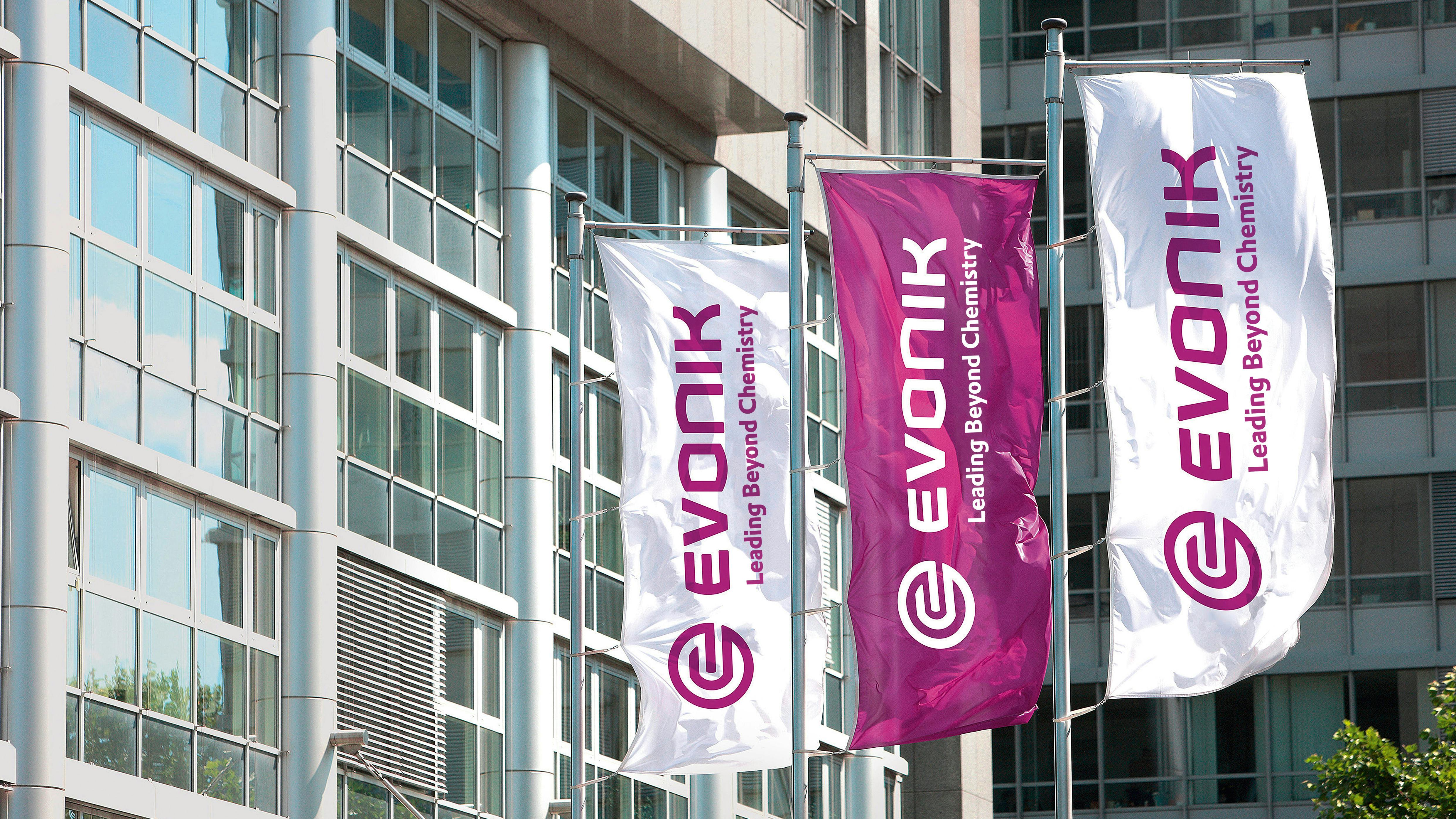 Three Evonik logo flag banners at company headquarters in Germany