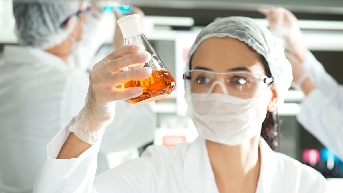 Scientist holds up beaker filled with liquid chemicals