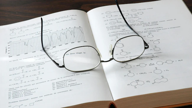 Open chemistry book showing formulas and graphs with eyesglasses on top of the pages