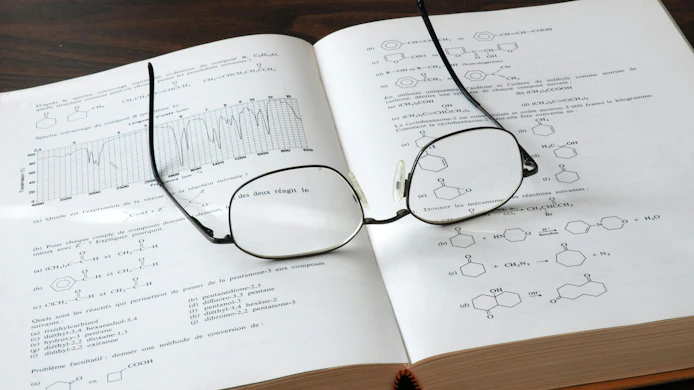 Open chemistry book showing formulas and graphs with eyesglasses on top of the pages