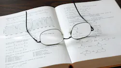 Open chemistry book showing formulas and graphs with eyesglasses on top of the pages