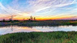 view of Louisiana landscape with river and marshlands against a colorful sky