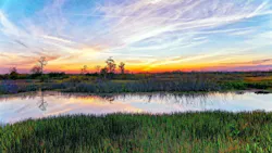view of Louisiana landscape with river and marshlands against a colorful sky