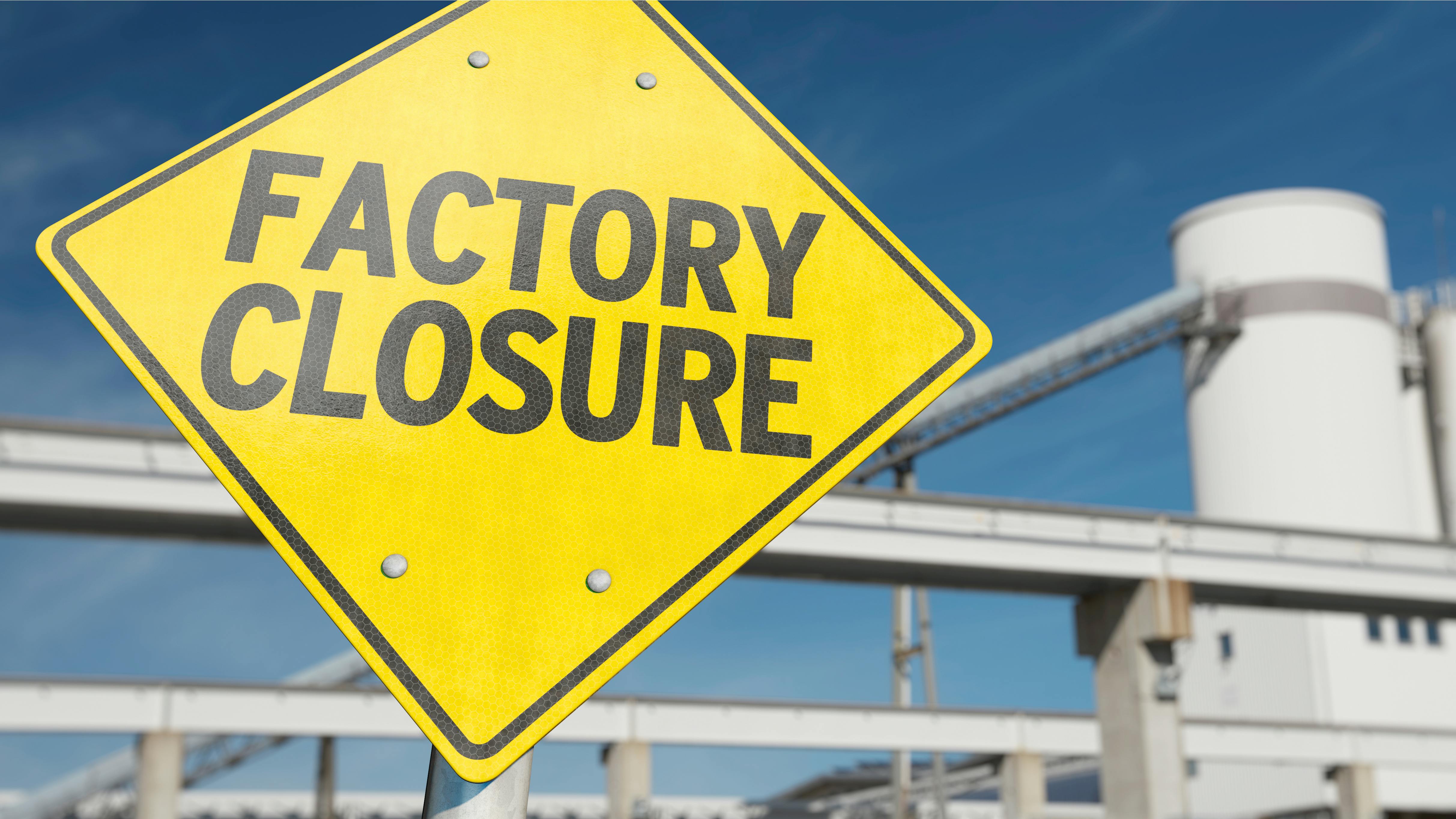 Factory Closure sign with plant tower and conveyor in background