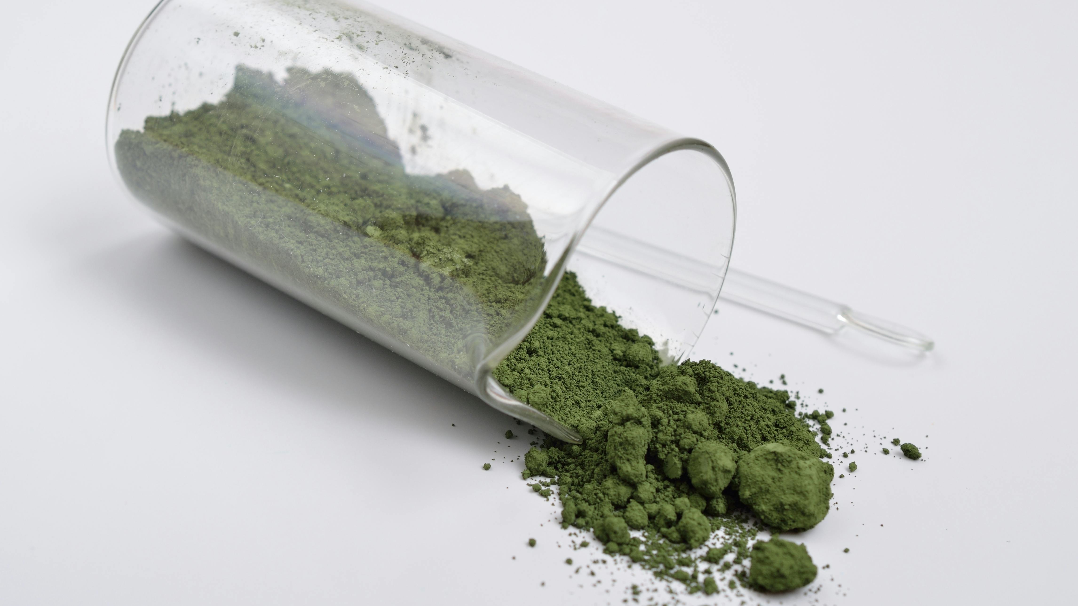 A glass vial on its side partially filled with Chromium III oxide powder
