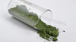 A glass vial on its side partially filled with Chromium III oxide powder