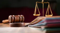 Judge's gavel in focus with legal folders and scale blurred in background