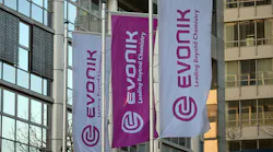 Flags bearing Evonik's corporate logo fly in front of the company's headquarters.