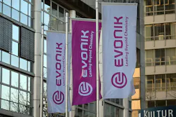 Flags bearing Evonik's corporate logo fly in front of the company's headquarters.