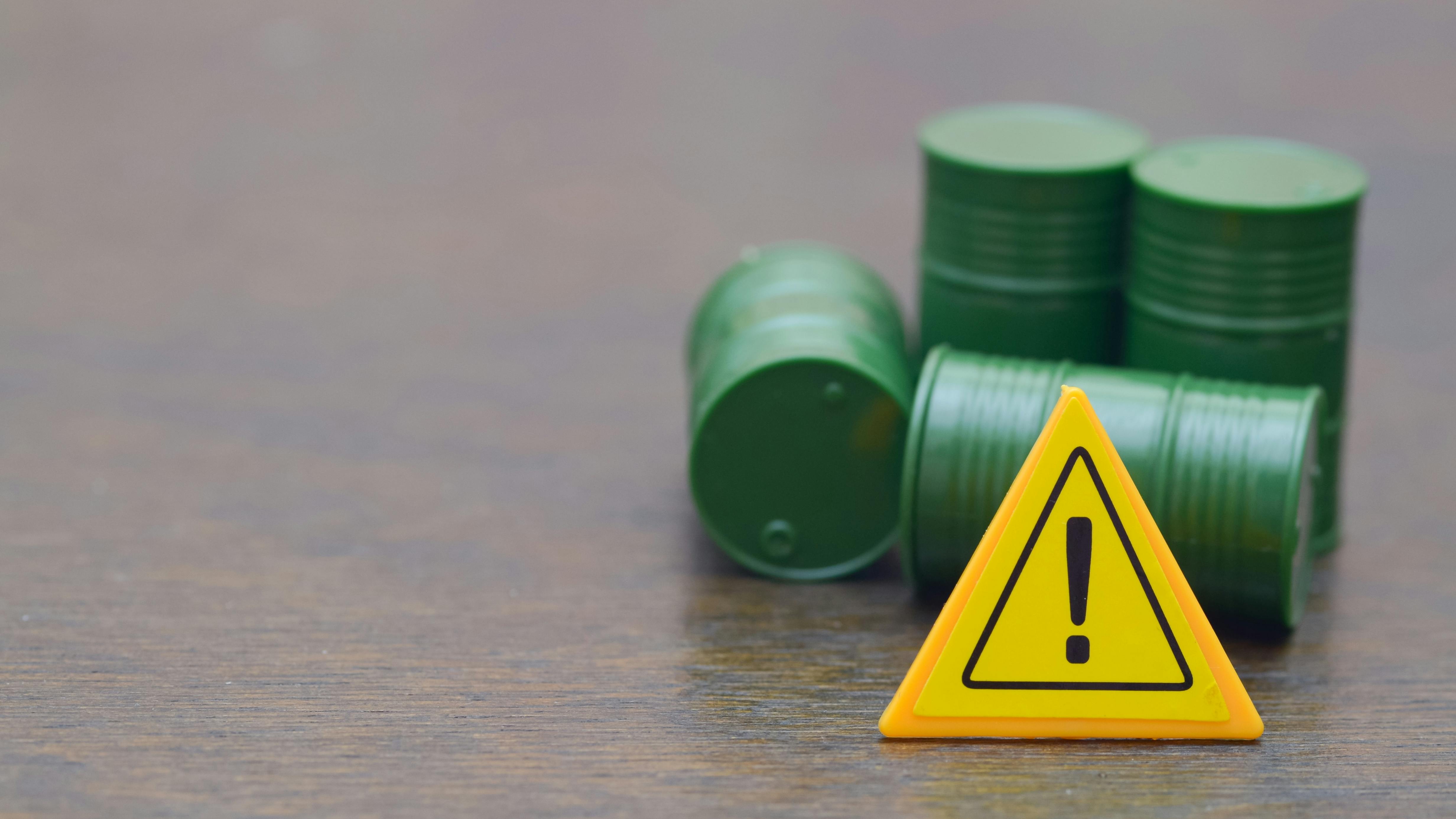 Caution Sign with Green Barrels Symbolizing Hazardous Waste and Environmental Risk