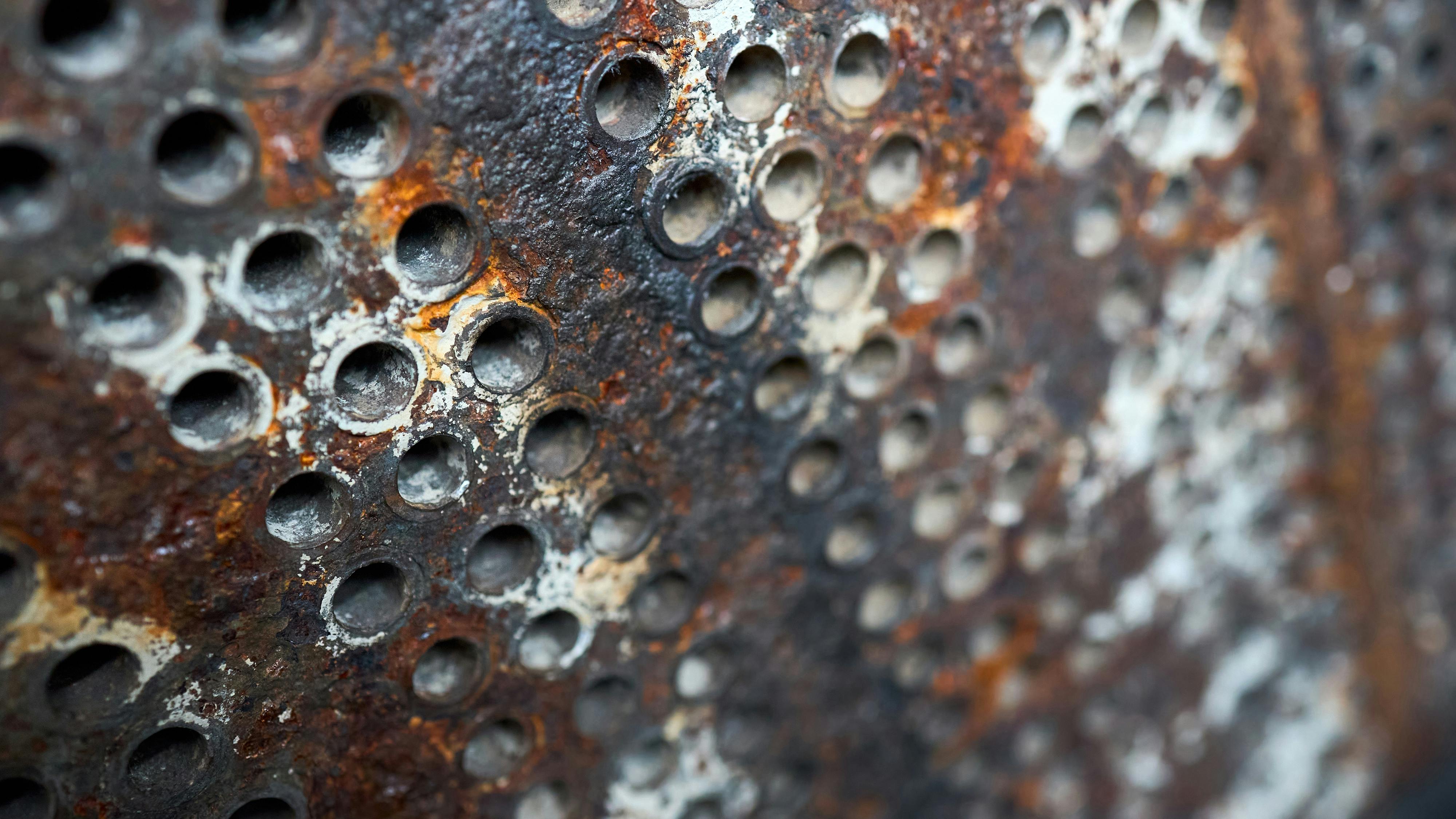 Tube sheet or plate of heat exchanger boiler closeup texture selective focus background opened for inspection maintenance or cleaning from insoluble hard mineral deposits salts scale and corrosion.