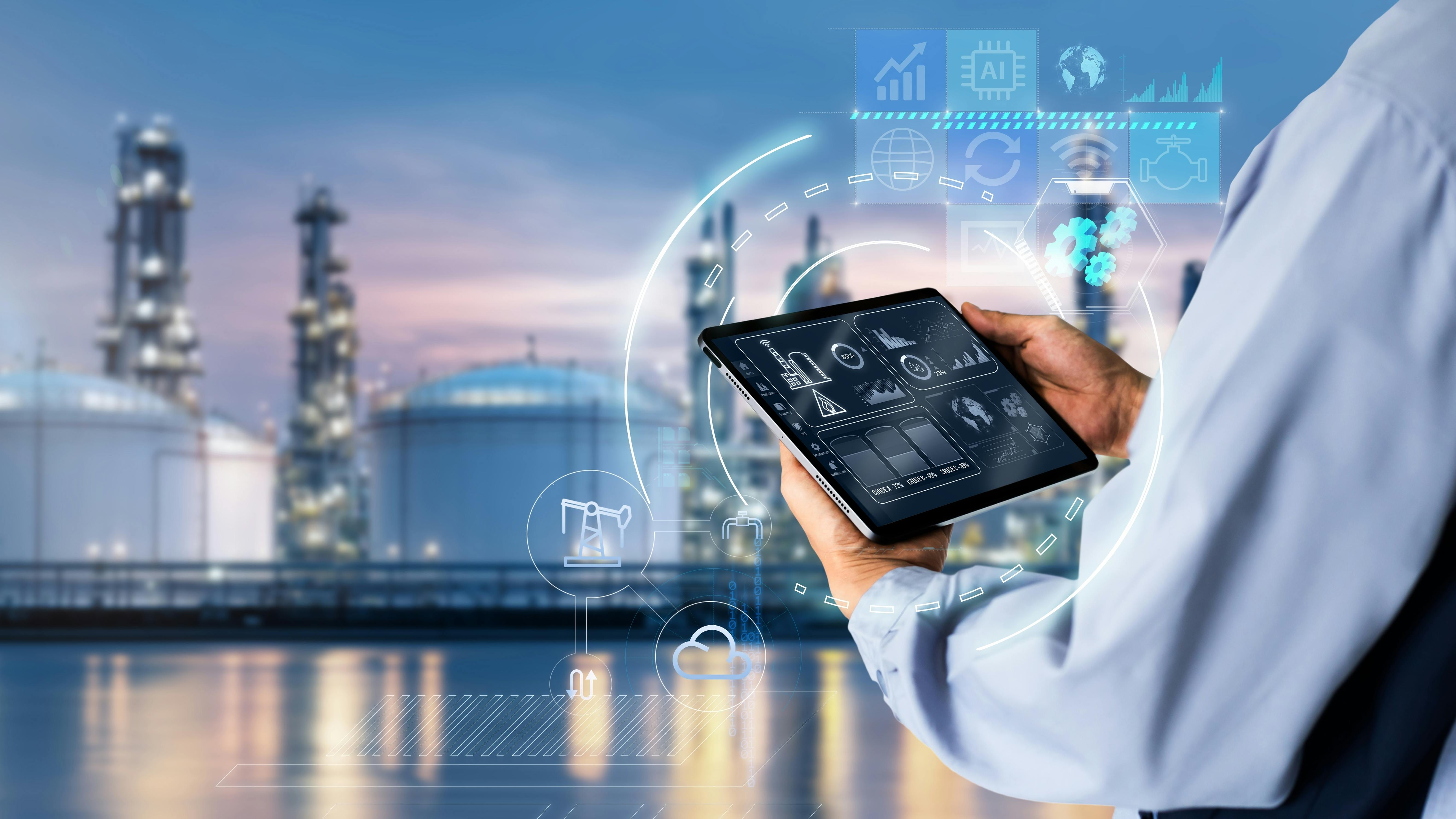 Industrial facility with processing towers in the background and an operator holding a tablet displaying plant data, surrounded by digital interface graphics representing AI, automation, analytics and connected process operations