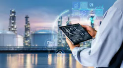 Industrial facility with processing towers in the background and an operator holding a tablet displaying plant data, surrounded by digital interface graphics representing AI, automation, analytics and connected process operations