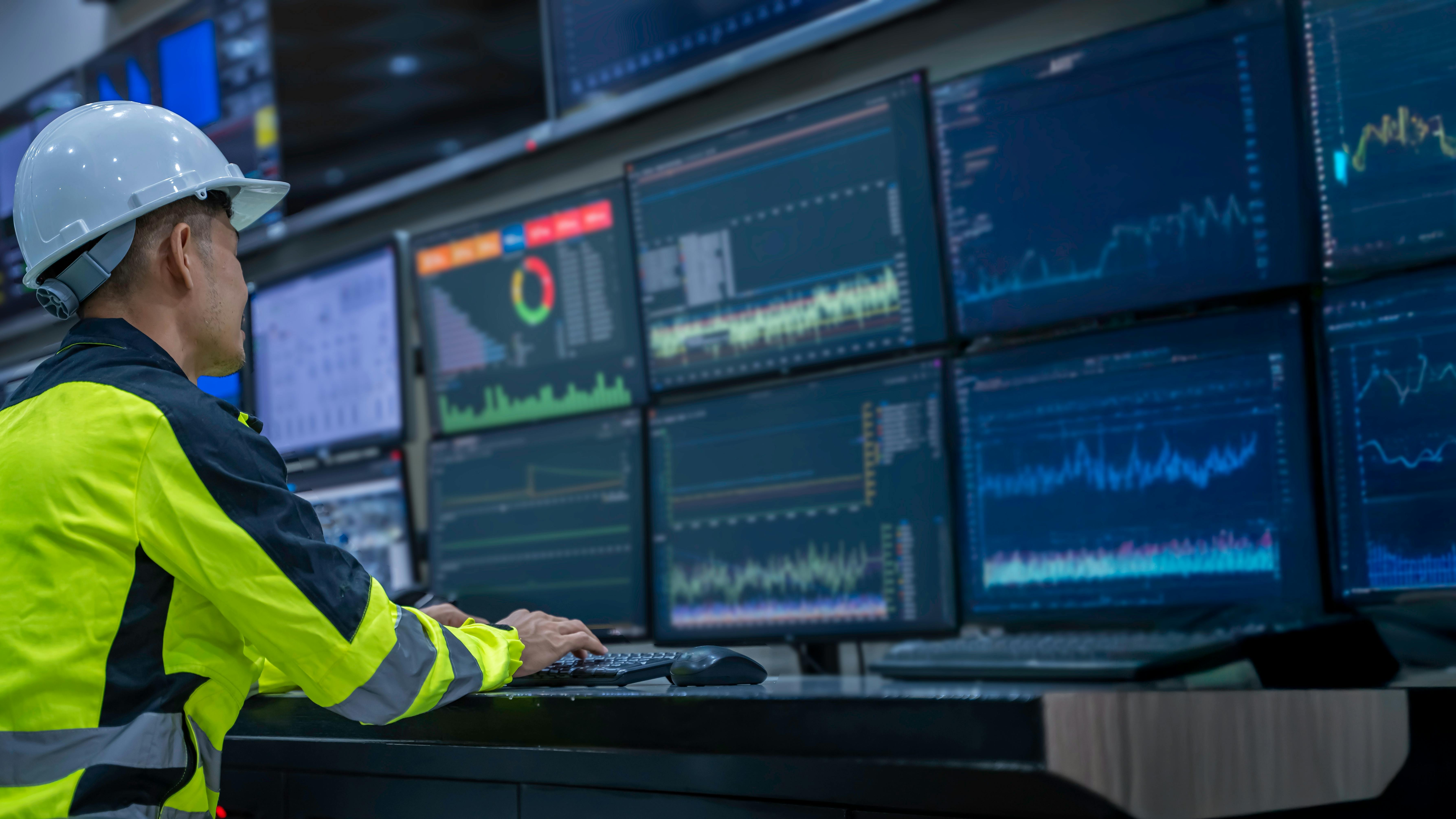 Engineer working in front of display screens in control room