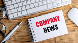 Notepad with text company news on a wooden desk with keyboard, mouse, pen and glasses .